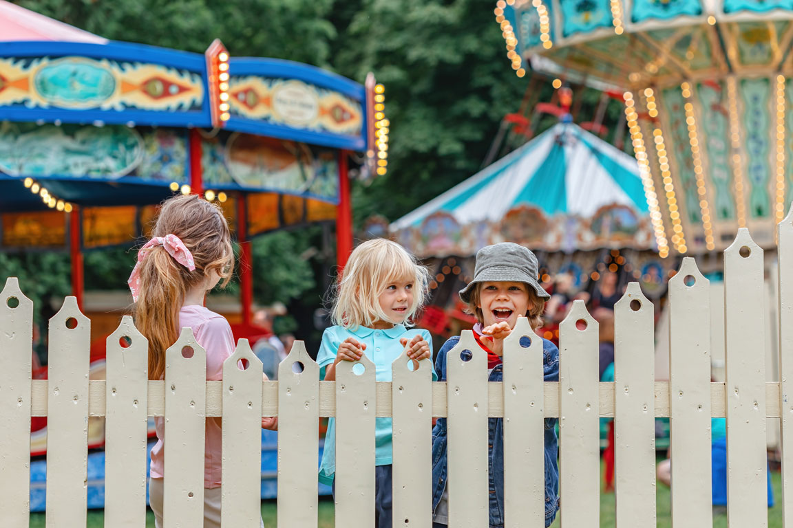 brothers-and-sister-standing-by-the-fence campers at a carnival